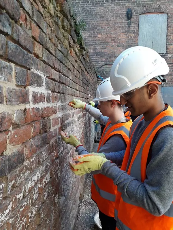 construction student using traditional lime mortar for repointing