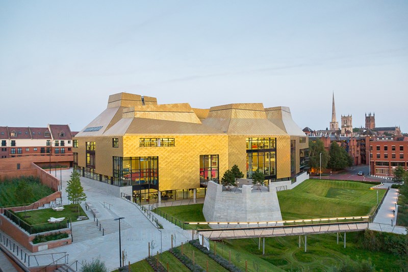 A wide shot of the The Hive, which is boxy with large windows. The exterior is a shiny gold.
